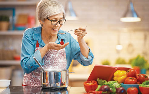 Healthy food at home. Happy woman is preparing vegetables and fruit in the kitchen.